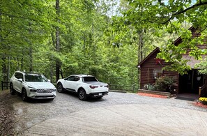 Two white SUVs parked in front of a rustic cabin with a wooden exterior and a red star decoration.