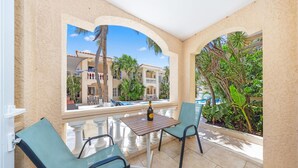 A balcony with a table and chairs, overlooking a pool and buildings. - Charming Condo in Prime Location @ Wacamaya Condos (Noord)