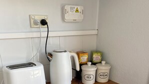 A kitchenette with a toaster, kettle, Twinings tea boxes, and sugar and tea containers. - Sun Kissed Studio  (Motueka)