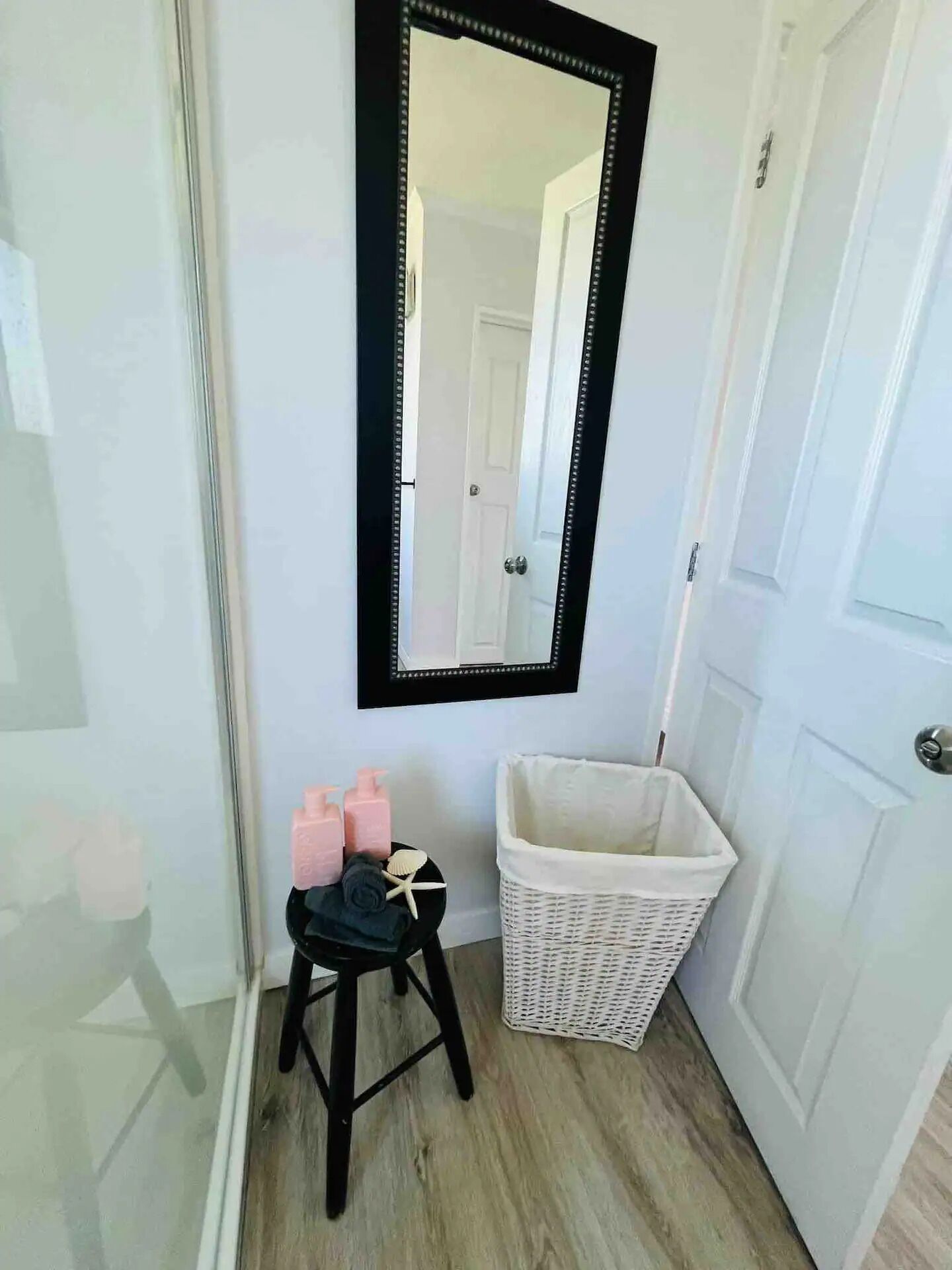 A bathroom with a white sink, a mirror, and a small stool.