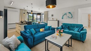 A modern living room with two blue sofas, a white coffee table, and a kitchen area in the background. - 78 (Medulin)