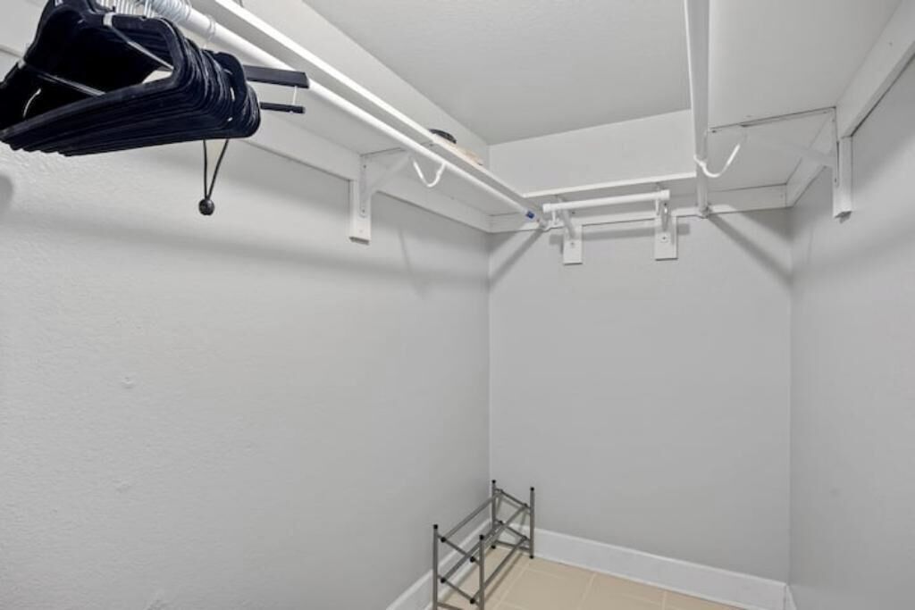 Een hoek van een kamer met witte muren, een metalen rek en een plafond met witte leidingen.