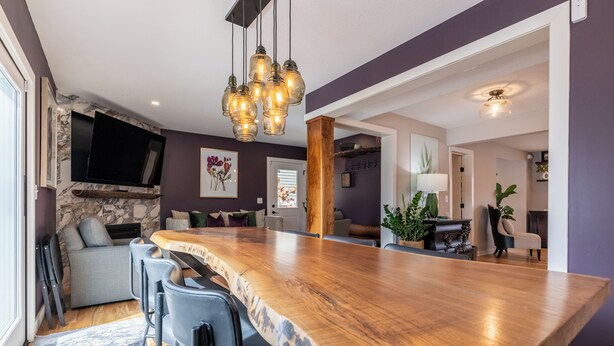 A modern kitchen with a large island, bar stools, a flat-screen TV, and a wooden accent wall.