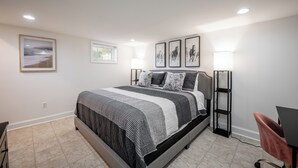 Quarto com cama, luminárias de cabeceira, escrivaninha e uma cadeira.