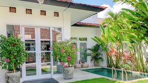 A house with a swimming pool, a well-maintained lawn, and various potted plants. - LANE HOUSE 1 (Canggu)