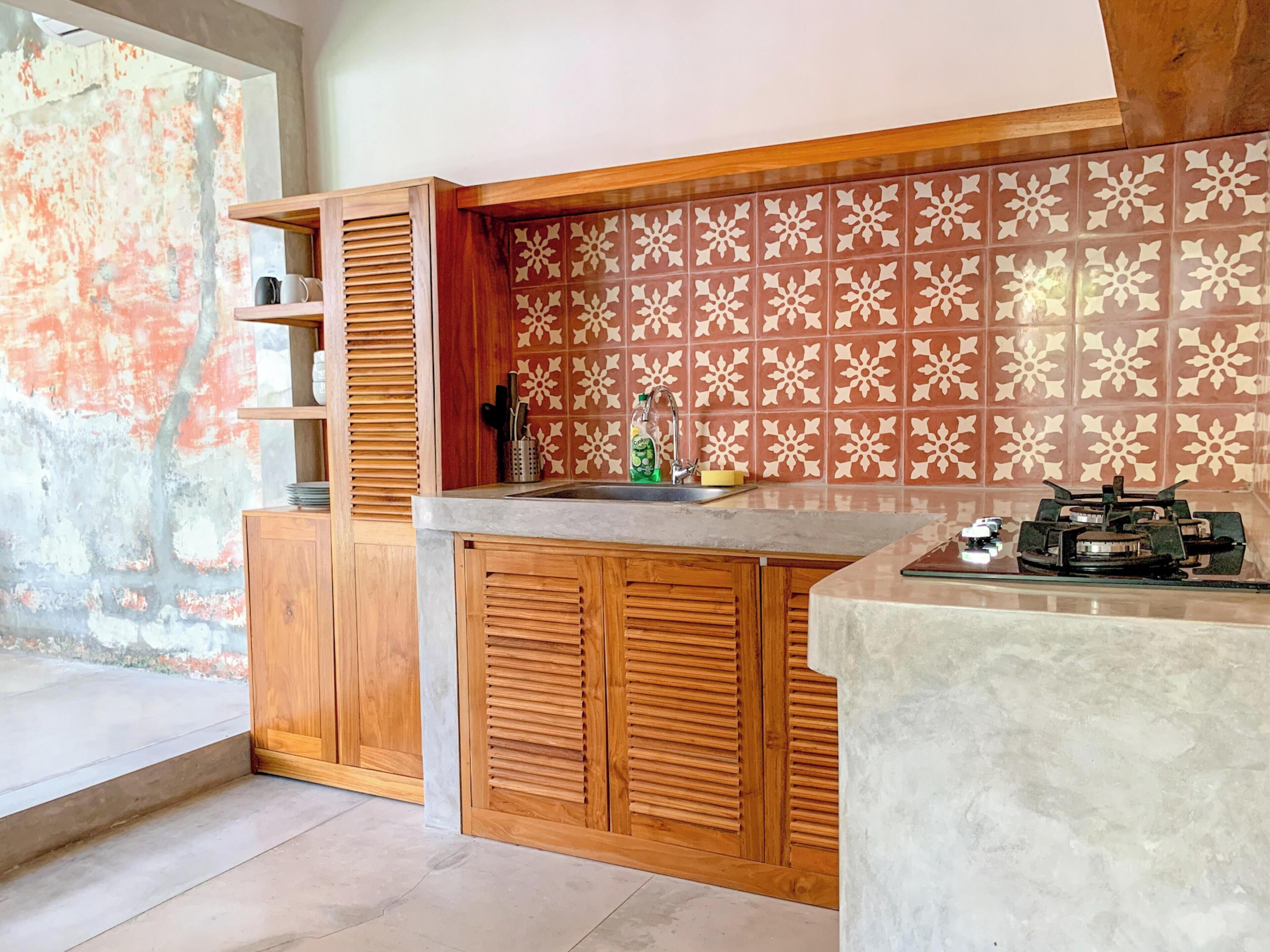 Una cocina con armarios de madera, salpicadero de azulejos y una estufa a gas.