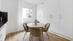 A modern kitchen with white cabinets, a black countertop, and a round dining table with two chairs.