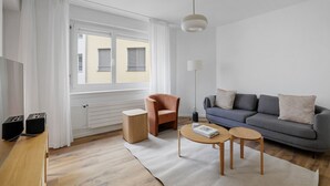 A modern living room with a grey sofa, a wooden coffee table, a brown armchair, and a floor lamp.