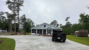 A house with a porch, a truck parked in front, and a shed in the background. - Cozy 4-bedroom house in welcoming Longs with WiFi, AC (Longs)