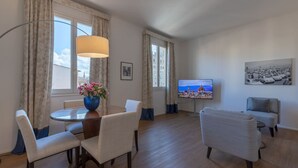 Una sala de estar moderna con comedor, televisión y un cuadro en la pared.