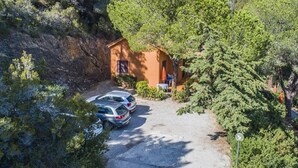 A small building with a gravel driveway and parked cars. - Appartamento Collina sul Golfo 14 (Porto Azzurro)