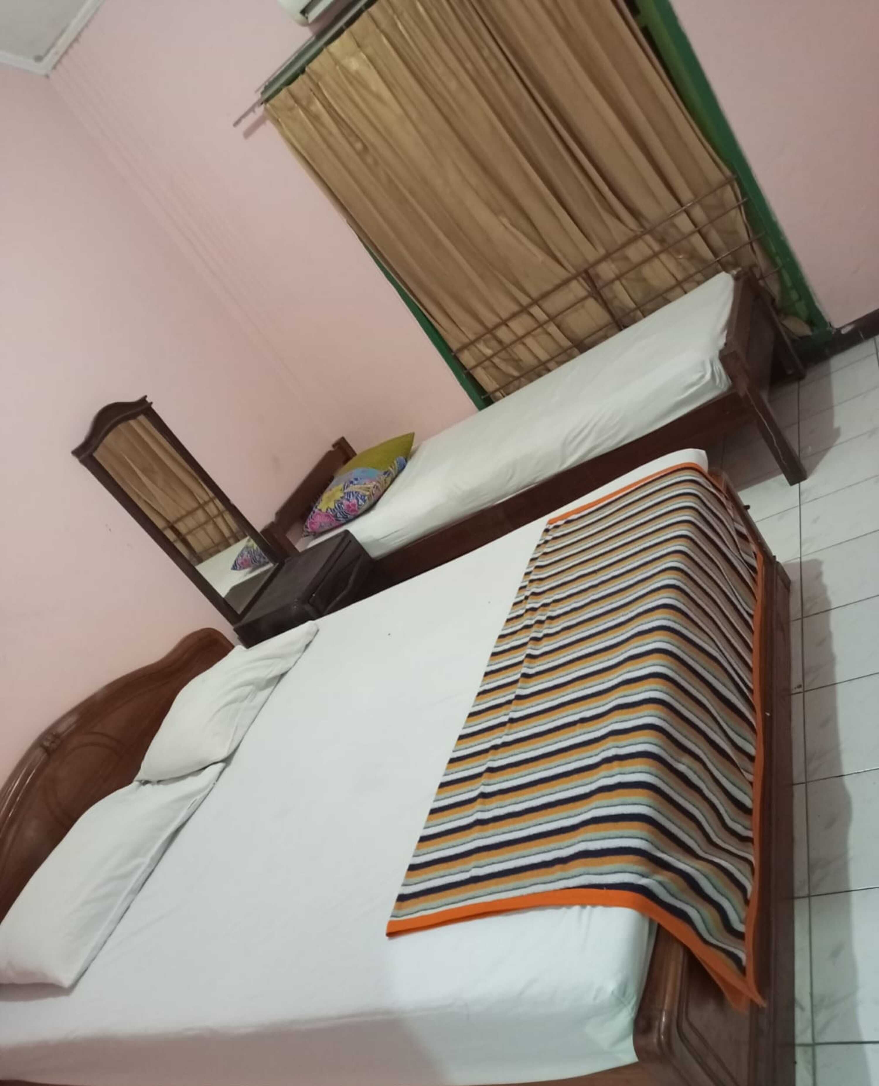 Una habitación con dos camas, un espejo, un armario y una mesita.