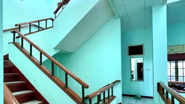 A staircase with wooden handrails and a tiled floor, leading to an upper level.