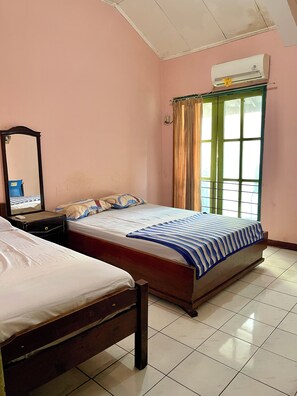A bedroom with two beds, a mirror, a nightstand, an air conditioner, and a window with curtains. - Hotel Tirtonadi Permai (Surakarta)