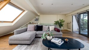 Eine moderne Loftlösung mit großem Oberlicht, einem Ecksofa, einem schwarzen Couchtisch und einem Topfpflanzen.