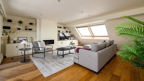 Ein modernes Wohnzimmer mit Sofa, Couchtisch und Fernseher, ein Essbereich mit Tisch und Stühlen sowie ein großes Fenster mit Aussicht.