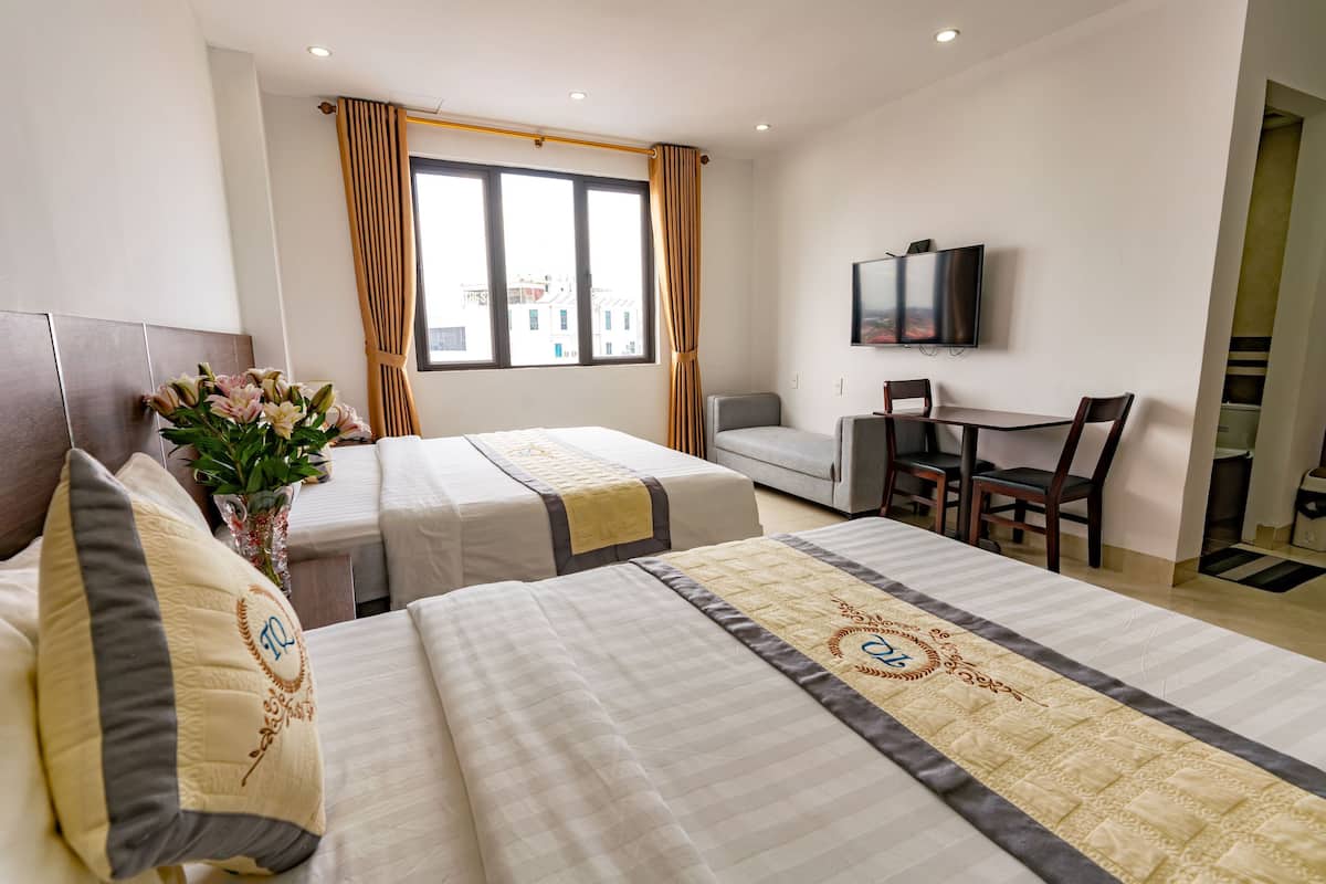 Une chambre d’hôtel avec deux lits, un bureau, une chaise, une télévision et une fenêtre avec des rideaux.