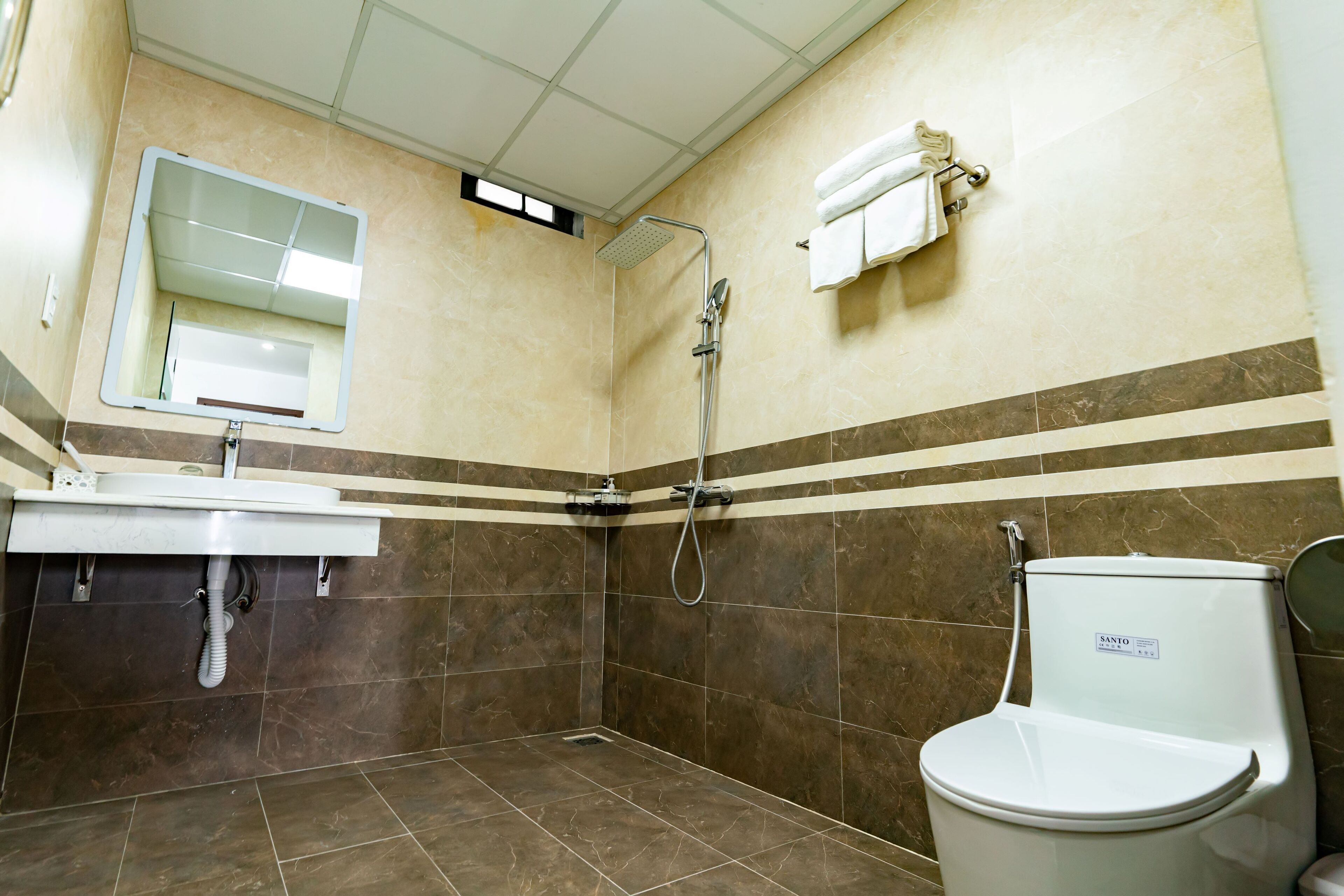 Une salle de bain équipée d’une douche, de toilettes, d’un lavabo et d’un miroir.