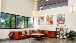 Un amplio salón con un gran ventanal, un sofá modular, una mesa de centro y obras de arte en las paredes.