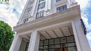 Un edificio de varios pisos con una entrada imponente, amplias ventanas y una escalera que conduce a la entrada.
