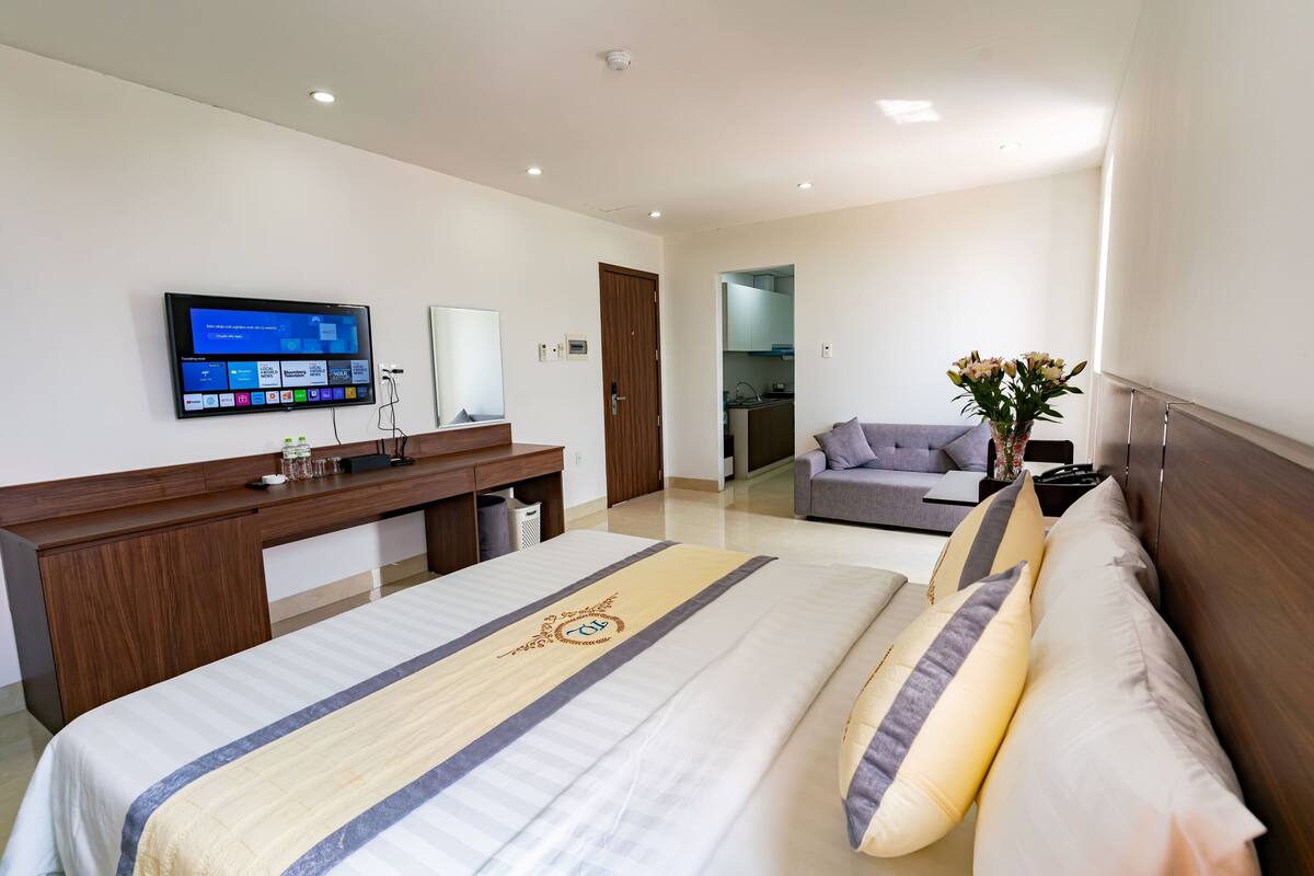 Une chambre d’hôtel avec un lit, un bureau, une télévision et un canapé.
