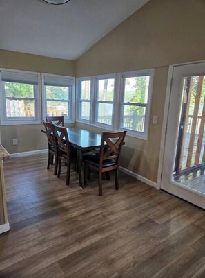 Enjoy meals in this dining area with a large table and six chairs, surrounded by large windows and a sliding glass door leading to an outdoor space.