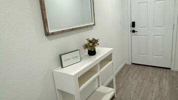 A hallway with a white console table, a framed mirror, and a door.