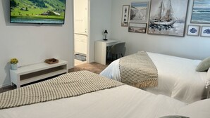Un dormitorio con dos camas, un escritorio, una silla, un televisor y obras de arte en la pared.