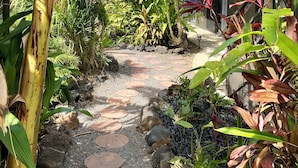 Ein tropischer Gartenpfad mit Holzterrasse und üppiger Vegetation.