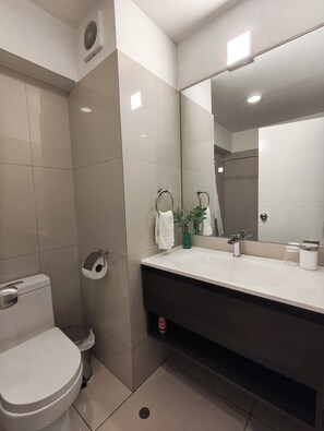 Ein modernes Badezimmer mit Toilette, Waschbecken und Spiegel.