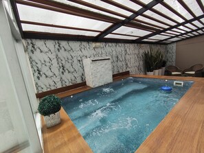 Ein Wellnessbereich mit Whirlpool, Holzboden und einer Decke mit Dachfenstern.