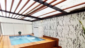 Ein Whirlpool mit Holzstufen und einer Wand mit Marmoroptik.