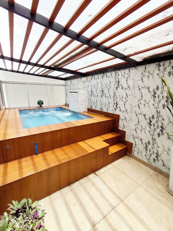 Ein Whirlpool mit Holzstufen und einer Wand mit Marmoroptik.