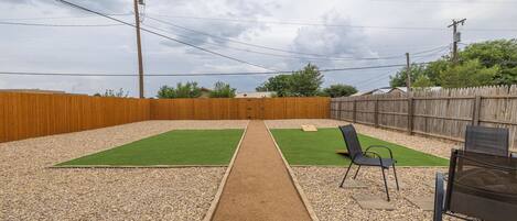 Een achtertuin met twee grasvelden, een grindpad en een houten omheining.