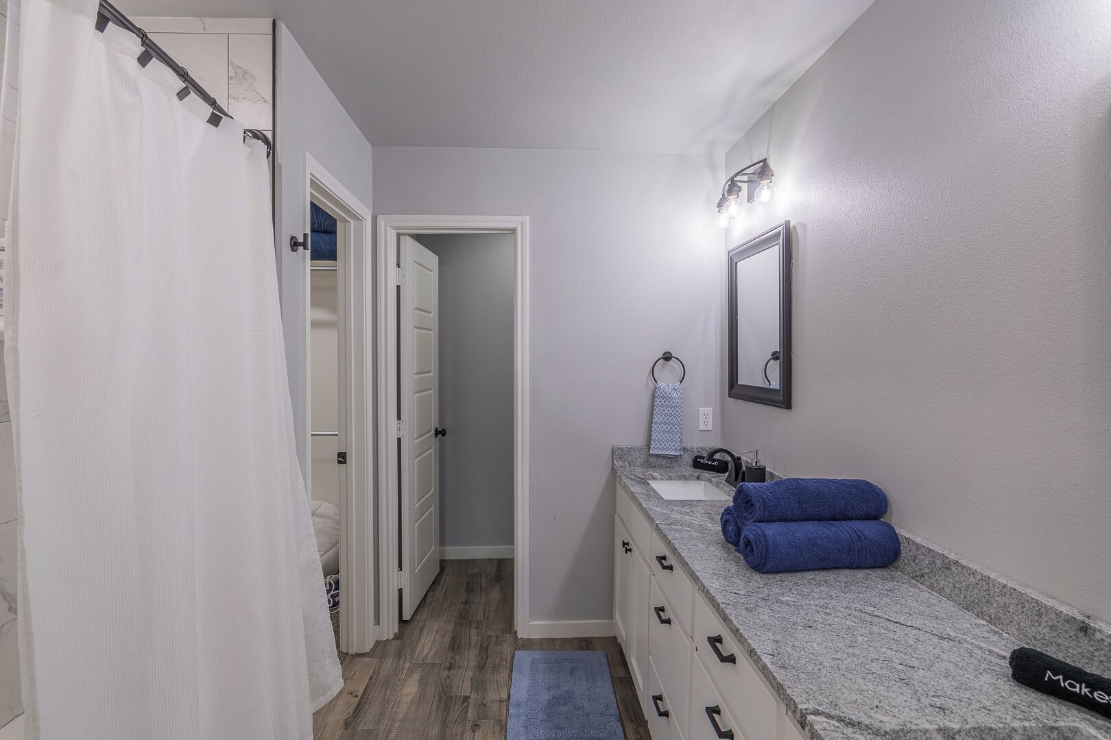 A bathroom with a shower curtain, a sink with a towel, and a mirror.