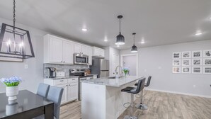 A modern kitchen with white cabinets, stainless steel appliances, and a central island with bar stools.