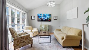 Ein Wohnzimmer mit großem Fenster, Fernseher, Couchtisch und zwei Sofas.