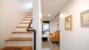A modern interior with a wooden staircase, a sofa, and a mirror on the wall. - Miller Loft at Container Park (Wilmington)