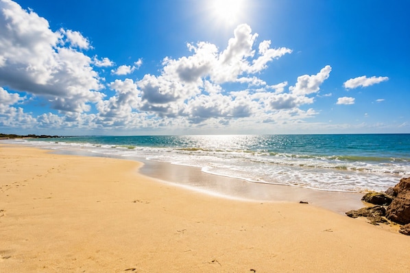 A beach with clear skies, calm waves, and a sandy shore.