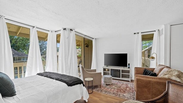 A bedroom with a bed, a TV, a sofa, and a small table.