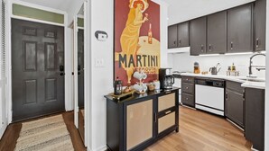 A modern kitchen with dark cabinets, a white dishwasher, and a coffee machine.