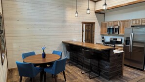 A modern kitchen with wooden cabinetry, a central island, and a dining area with blue chairs.