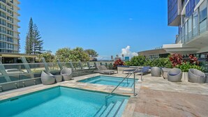 A rooftop pool area with two pools, lounge chairs, and a view of the cityscape. - Rhapsody Stunning Ocean Views Apartment - CoastHM (Surfers Paradise)