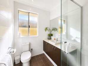 Un baño moderno con inodoro, lavamanos y ducha.