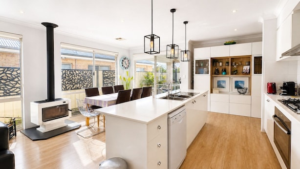 Una cocina moderna con una isla central, horno empotrado e iluminación colgante.