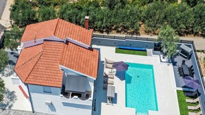 Une vue aérienne d’une maison avec une piscine, un patio couvert et un jardin.