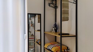 A compact room with a mirrored closet door, a shelf with a polka-dotted cloth, and a yellow pillow with black stripes. - A-1 · Cosy Modern Studio With Balcony in Blloku (Tiranë)