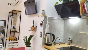 A modern kitchen with a flat-screen TV, a kettle, and various plants. - A-1 · Cosy Modern Studio With Balcony in Blloku (Tiranë)