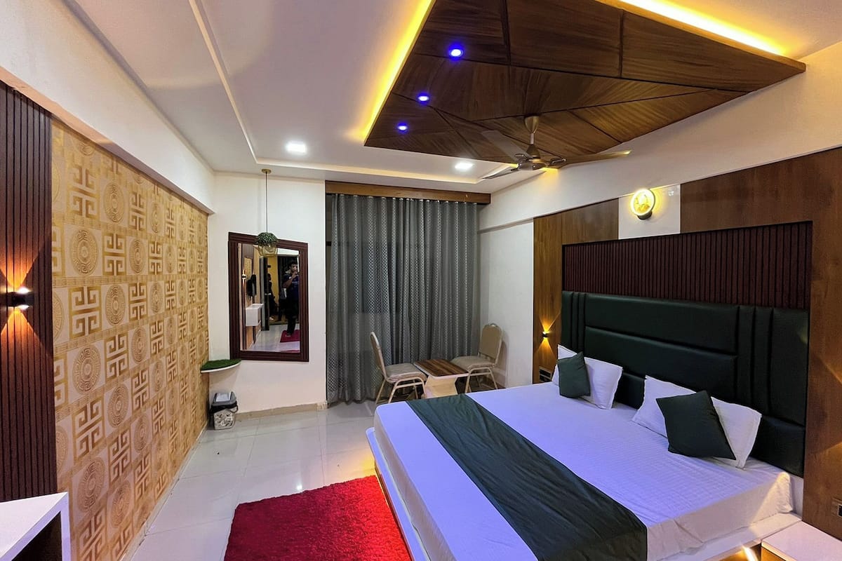 A modern hotel room with a large bed, a desk, and a mirror.