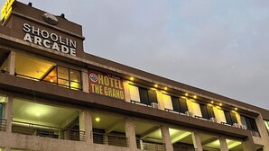 En byggnad med flera våningar, där det finns en skylt med texten ”Shoolin Arcade” och en annan skylt med texten ”Hotel The Grand” på tredje våningen.